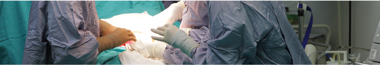 A baby sleeps peacefully on its back in a crib, covered with a brown knitted blanket. The crib bars and a soft blue background are visible.